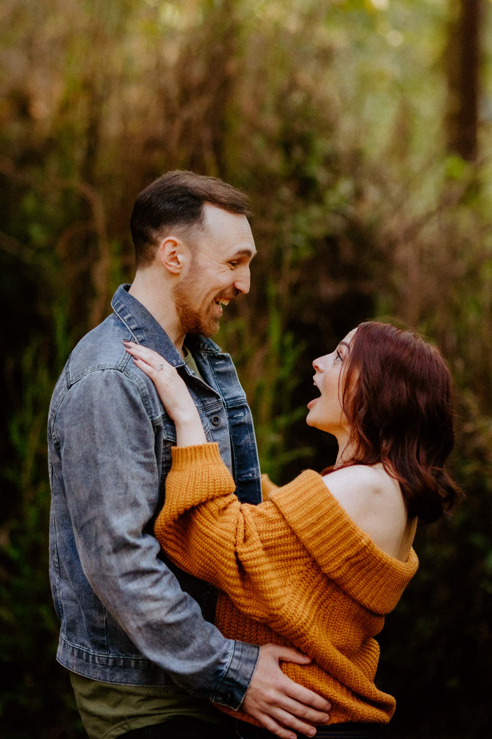 The couple's playful and romantic moment captured amidst the stunning redwood forest.