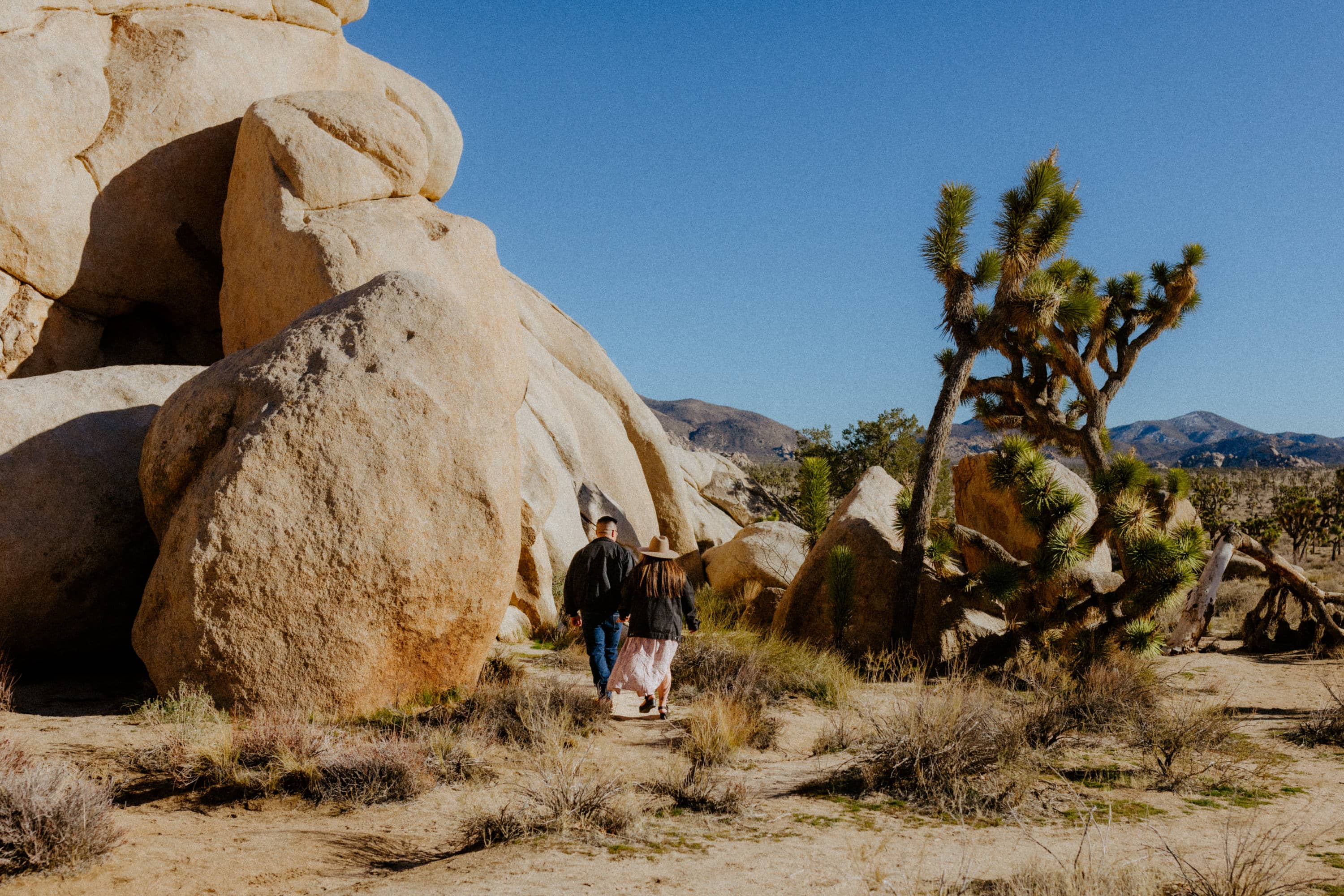 Playful couple exploring Joshua Tree National Park during their engagement session.