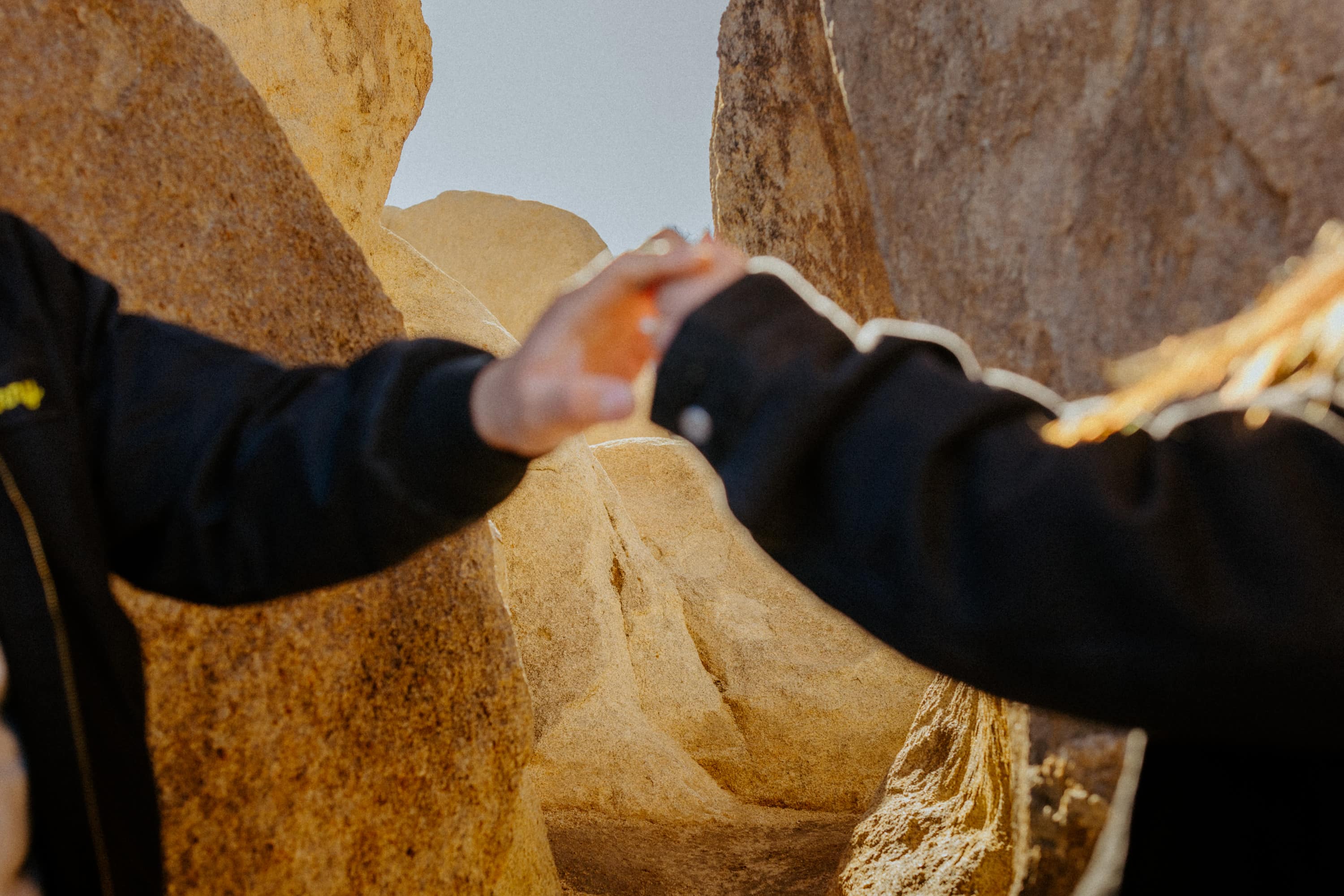 Intertwined hands at Joshua Tree National Park engagement, symbolizing their love.