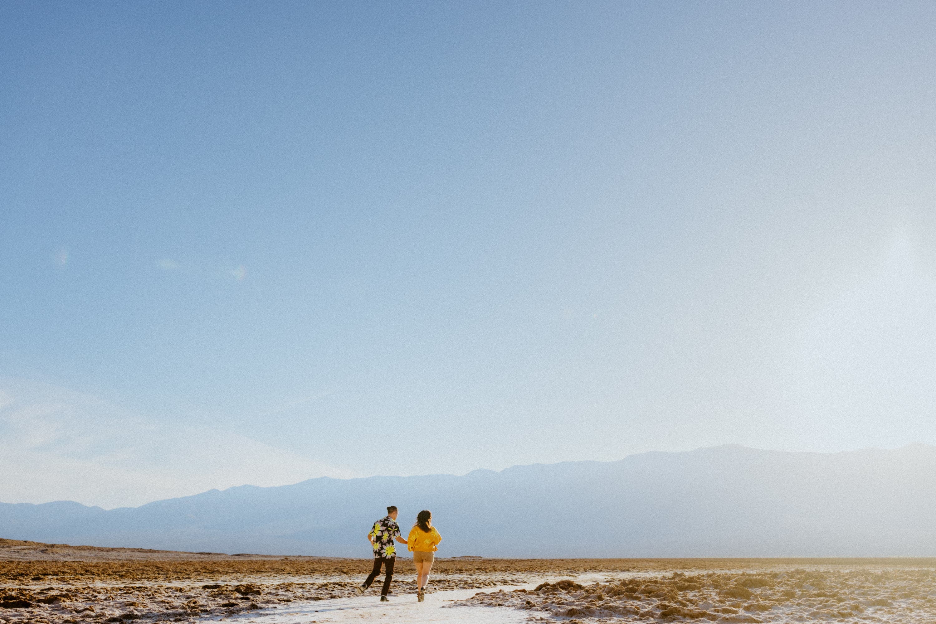 Playful couple framed by salt flats in the lowest point of North America for their Death Valley National Park engagement session.
